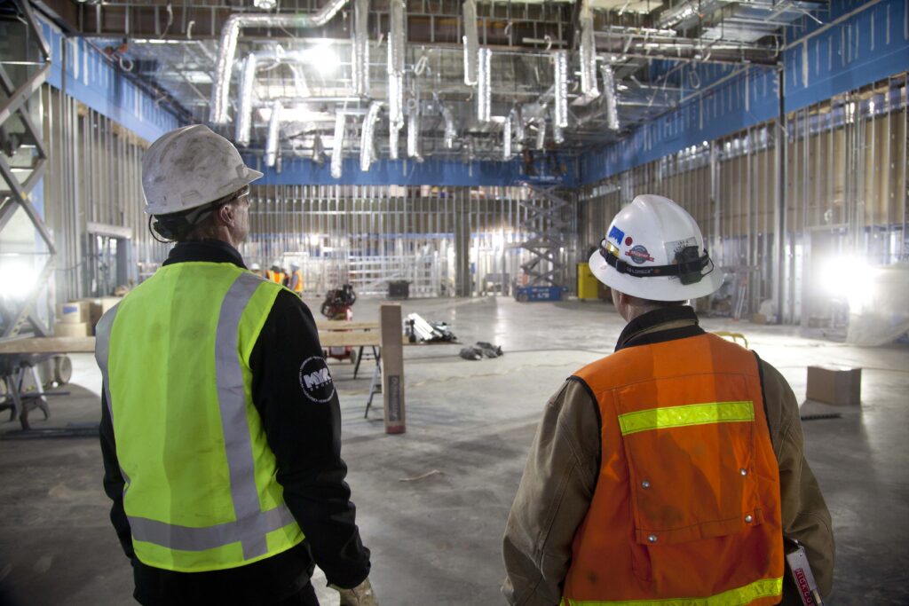 Two men in a large room observing pipes