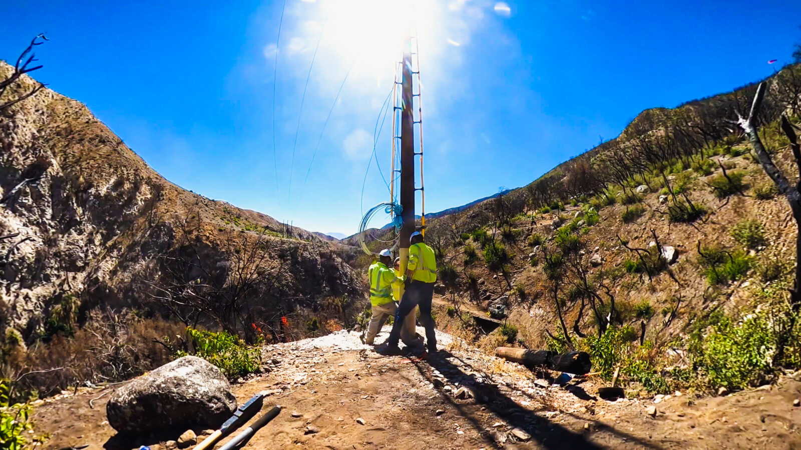 Two Harlan Electric workers placing a power line pole correctly into the ground